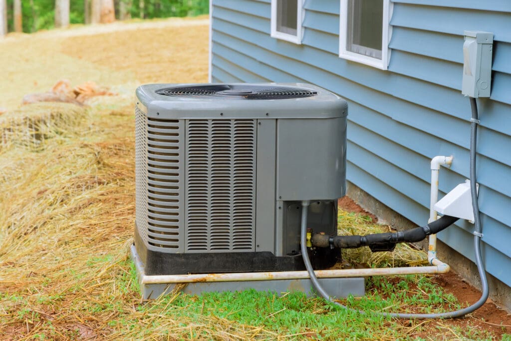 Air conditioner outside of a home with blue siding