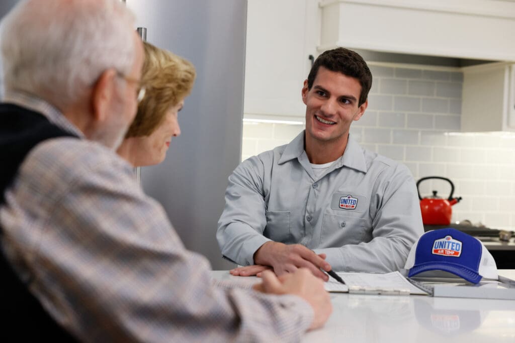 UAT technician talking to homeowners at a kitchen table