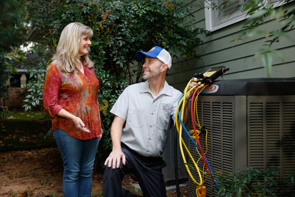 HVAC technician checking refrigerant levels while talking to a homeowner