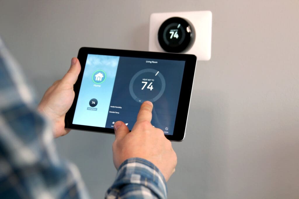 Person adjusting a temperature using a tablet with smart home app in modern living room.