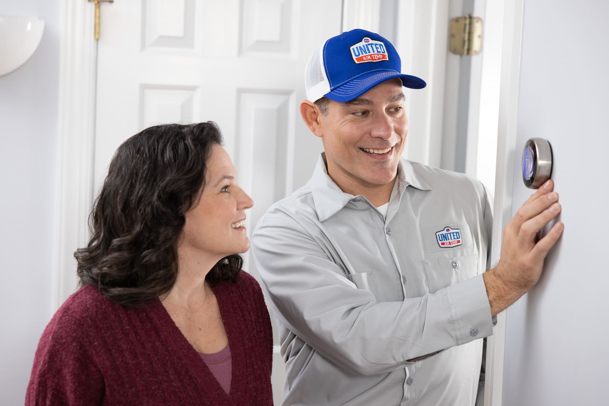 UAT technician and homeowner adjusting a smart thermostat
