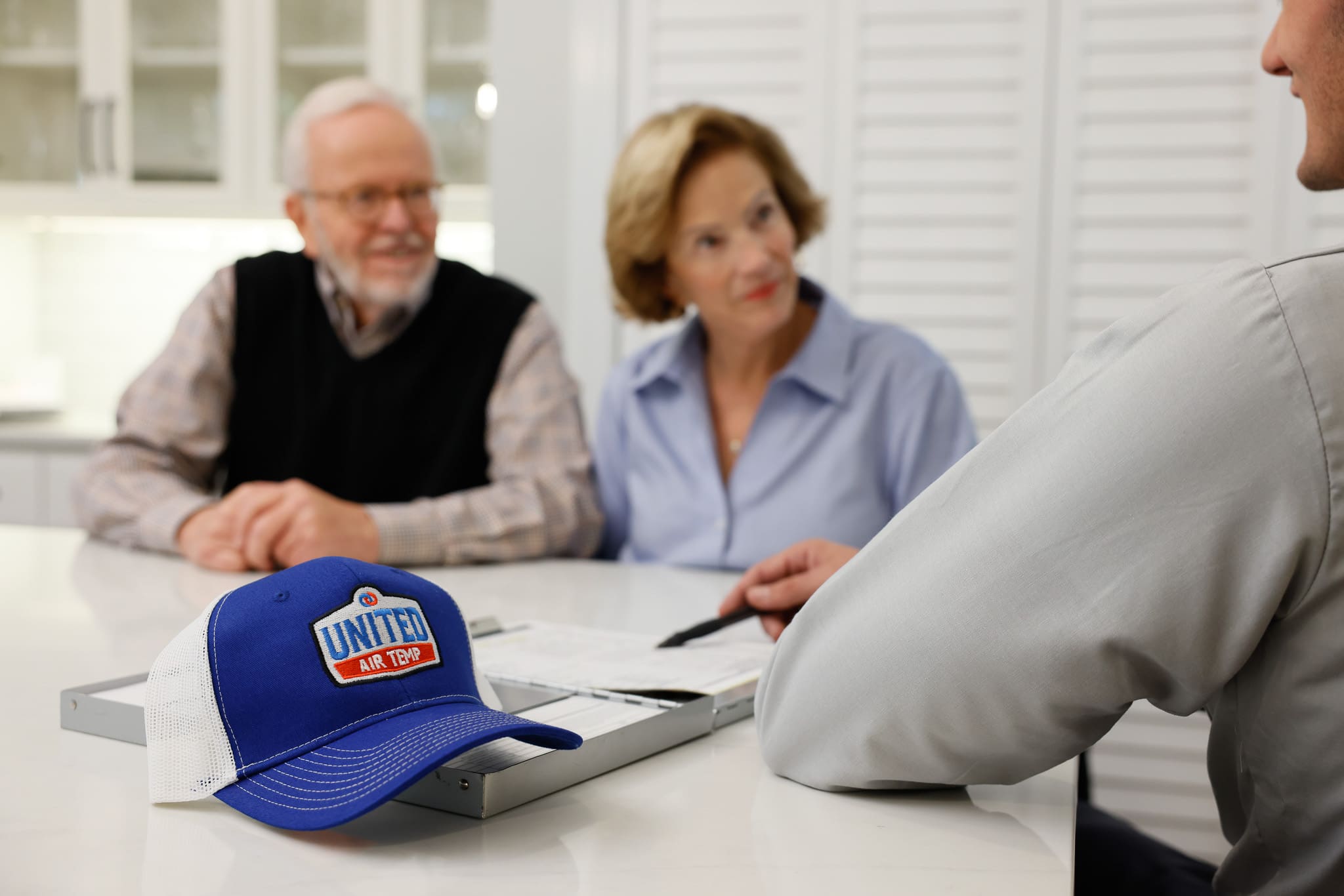 UAT technician sitting at a table talking to homeowners
