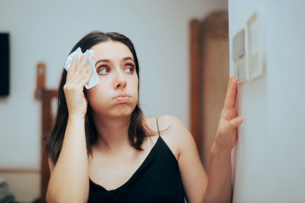 Woman sweating and dabbing a tissue on her forehead