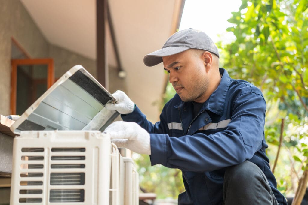 Technician tuning up an outdoor HVAC unit.