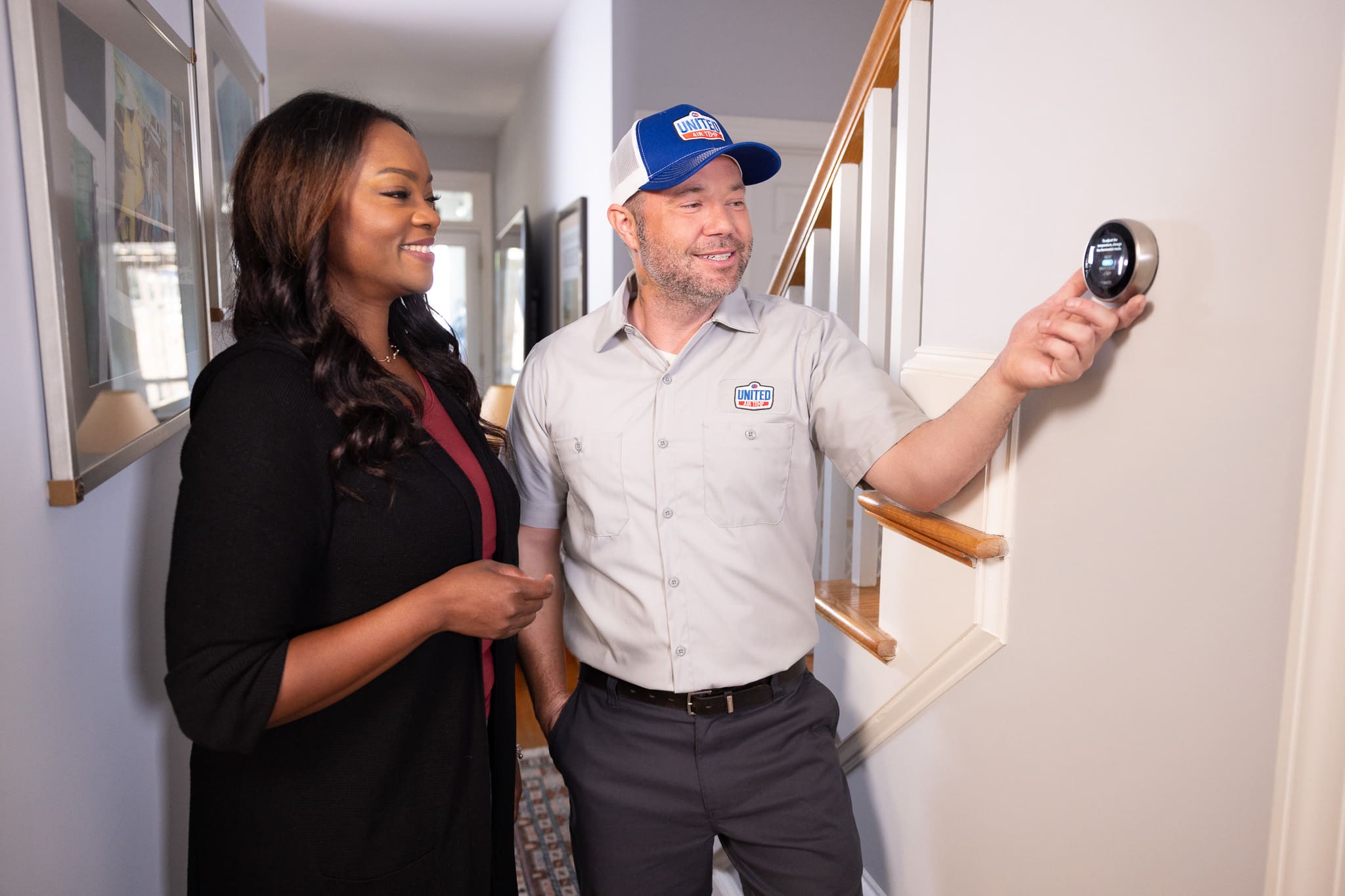 Technician showing homeowner how to use a smart thermostat