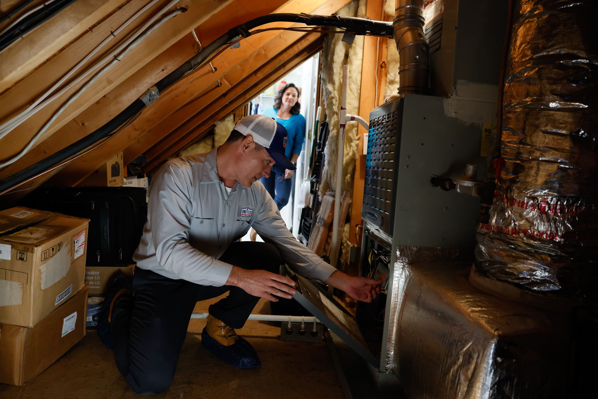 Technician installing an HVAC system in a home's unfinished attic.