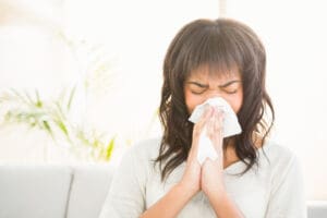 woman sneezing on couch